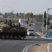 Illustration : Des soldats israéliens traversant une route principale dans un véhicule blindé de transport de troupes (APC), à la jonction de Shaar Hanegev près de Sderot, le 8 octobre 2023. (Crédit : Menahem Kahana/AFP)