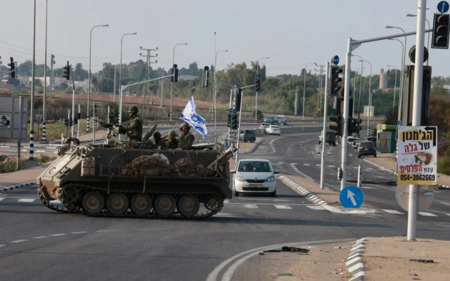 Illustration : Des soldats israéliens traversant une route principale dans un véhicule blindé de transport de troupes (APC), à la jonction de Shaar Hanegev près de Sderot, le 8 octobre 2023. (Crédit : Menahem Kahana/AFP)