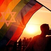 Deux hommes s'embrassent en tenant un drapeau arc-en-ciel au centre duquel se trouve une étoile de David à Tel Aviv, le 6 juin 2024. (Crédit : JACK GUEZ / AFP)