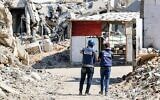 Des journalistes filmant devant des bâtiments détruits dans le camp de réfugiés de Jabaliya, dans le nord de la bande de Gaza, le 9 octobre 2024. (Crédit : Omar Al-Qattaa/AFP)