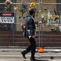 Un membre de la communauté juive lisant des messages accrochés à une clôture où des fleurs ont été déposées, à la synagogue Adass Israel, dans la banlieue de Ripponlea, à Melbourne, le 9 décembre 2024. (Crédit : Martin Keep/AFP)