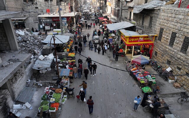 Des personnes marchant dans une rue commerçante bordée de bâtiments effondrés, détruits pendant la guerre civile syrienne, dans la ville d'Alep, au nord de la Syrie, le premier jour du ramadan, le 1ᵉʳ mars 2025. (Crédit : Omar Haj Kadour/AFP) Des personnes marchant dans une rue commerçante bordée de bâtiments effondrés, détruits pendant la guerre civile syrienne, dans la ville d'Alep, au nord de la Syrie, le premier jour du ramadan, le 1ᵉʳ mars 2025. (Crédit : Omar Haj Kadour/AFP)