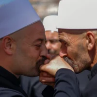 Des religieux druzes se saluent en attendant leurs homologues syriens venus leur rendre visite, au niveau d'une barrière frontalière gardée par des soldats israéliens, près du village de Majdal Shams sur le plateau du Golan, le 25 avril 2025. (Photo de Jalaa MAREY / AFP)