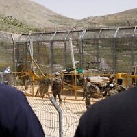 Des soldats israéliens montent la garde alors que des hommes druzes manifestent en solidarité avec la communauté druze syrienne, près de la barrière frontalière dans le village de Majdal Shams sur le plateau du Golan, le 30 avril 2025. (Jalaa Marey/AFP)