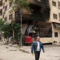 Un homme passe devant un bâtiment partiellement brûlé à la suite d'affrontements sectaires à Ashrafiyat Sahnaya près de Damas, en Syrie, le 1er mai 2025. (Crédit : Omar Haj Kadour/AFP)