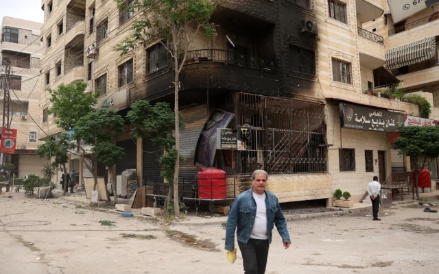 Un homme passe devant un bâtiment partiellement brûlé à la suite d'affrontements sectaires à Ashrafiyat Sahnaya près de Damas, en Syrie, le 1er mai 2025. (Crédit : Omar Haj Kadour/AFP)