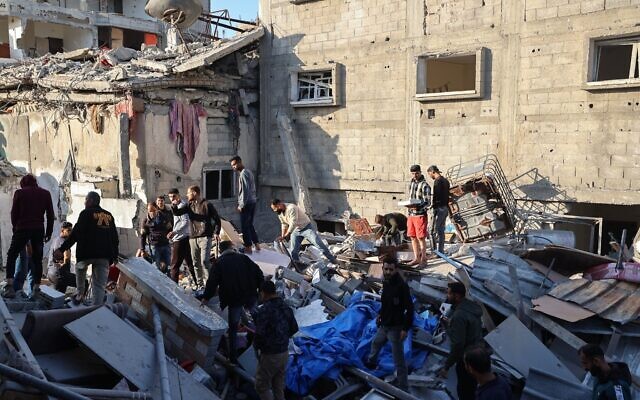 Des personnes recherchant des survivants dans les décombres d'un bâtiment touché par une frappe israélienne, à Bureij, dans le centre de la bande de Gaza, le 2 mai 2025. (Crédit : Eyad Baba/AFP)