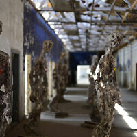 Une visiteuse passe devant l'installation « Statues Against Forgetting » de l'artiste britannique Stuart N. R. Wolfe dans un ancien atelier du camp de concentration de Ravensbrück, près de Fuerstenberg, au nord de Berlin, le 29 avril 2025. Ravensbrück, camp de concentration nazi réservé aux femmes de 1939 à 1945, a été libéré par les troupes soviétiques le 30 avril 2025. Le 80e anniversaire de la libération du camp sera célébré le 4 mai 2025. (Crédit : John MACDOUGALL / AFP)