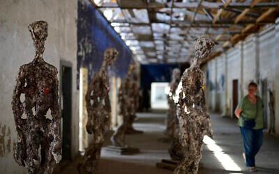 Une visiteuse passe devant l'installation « Statues Against Forgetting » de l'artiste britannique Stuart N. R. Wolfe dans un ancien atelier du camp de concentration de Ravensbrück, près de Fuerstenberg, au nord de Berlin, le 29 avril 2025. Ravensbrück, camp de concentration nazi réservé aux femmes de 1939 à 1945, a été libéré par les troupes soviétiques le 30 avril 2025. Le 80e anniversaire de la libération du camp sera célébré le 4 mai 2025. (Crédit : John MACDOUGALL / AFP)