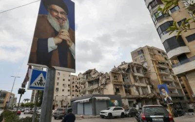 Dans le quartier de Ghobeiry, dans la banlieue sud de Beyrouth, des automobilistes passent devant des portraits du chef du Hezbollah libanais Hassan Nasrallah et des bâtiments endommagés par les frappes israéliennes lors de la récente guerre, à l'occasion du premier tour des élections municipales, le 4 mai 2025. (Crédit : ANWAR AMRO / AFP)