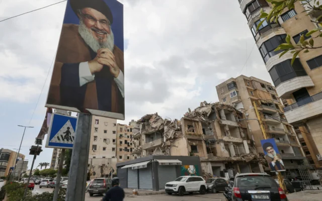 Dans le quartier de Ghobeiry, dans la banlieue sud de Beyrouth, des automobilistes passent devant des portraits du chef du Hezbollah libanais Hassan Nasrallah et des bâtiments endommagés par les frappes israéliennes lors de la récente guerre, à l'occasion du premier tour des élections municipales, le 4 mai 2025. (Crédit : ANWAR AMRO / AFP)