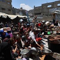 Des Palestiniens font la queue pour recevoir un repas chaud dans une cuisine caritative dans le camp de Nuseirat, dans le centre de la bande de Gaza, le 4 mai 2025 (Crédit : Eyad BABA / AFP)