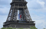 Un drapeau français géant est suspendu à la Tour Eiffel dans le cadre des cérémonies de commémoration du 80e anniversaire de la victoire en Europe du 8 mai 1945 et de la fin de la Seconde Guerre mondiale en Europe, à Paris, le 8 mai 2025. (Crédit : Thomas SAMSON / AFP)
