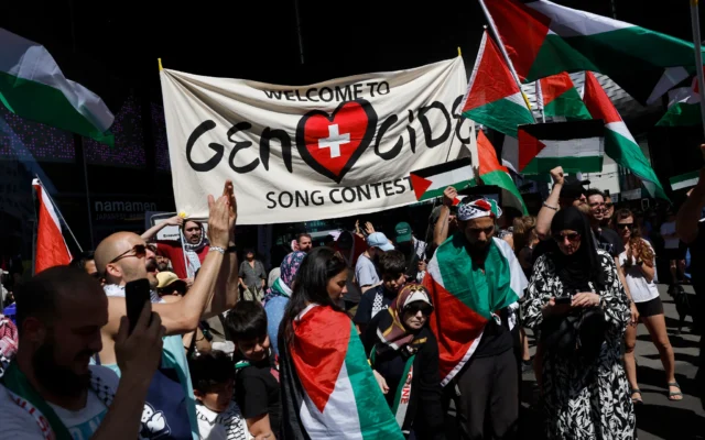 Des manifestants tiennent une bannière et des drapeaux palestiniens lors d'une manifestation contre la candidate d'Israël pendant la cérémonie d'ouverture du Concours Eurovision de la chanson 2025 à Bâle, le 11 mai 2025. (Crédit Stefan Wermuth / AFP) Des manifestants tiennent une bannière et des drapeaux palestiniens lors d'une manifestation contre la candidate d'Israël pendant la cérémonie d'ouverture du Concours Eurovision de la chanson 2025 à Bâle, le 11 mai 2025. (Crédit Stefan Wermuth / AFP)