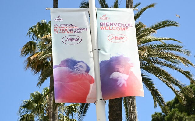 Une bannière annonçant le festival du film, près de palmiers, à la veille de la 78e édition du Festival de Cannes à Cannes, dans le sud de la France, le 12 mai 2025. (Crédit : Bertrand GUAY / AFP)