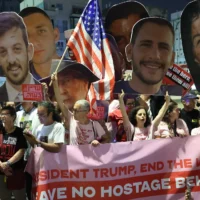 Des parents et des sympathisants d'Israéliens retenus en otage à Gaza par les terroristes palestiniens brandissent des pancartes et des drapeaux israéliens en demandant aux Etats-Unis d'intervenir pour leur libération, devant le bureau de l'ambassade des Etats-Unis à Tel Aviv, le 13 mai 2025. (Crédit : Jack Guez/AFP)