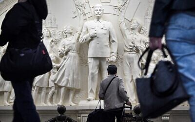 Des usagers de métro font une pause en passant devant le bas-relief récemment dévoilé représentant le dictateur soviétique Joseph Staline dans un passage de la station de métro Taganskaïa à Moscou, le 15 mai 2025. Le 15 mai 2025, les autorités moscovites ont dévoilé un bas-relief représentant Joseph Staline dans le métro de la capitale russe, alors que le Kremlin s'efforce depuis des années de réhabiliter le dictateur, en promouvant une version ultra-patriotique de l'histoire qui passe sous silence la répression de l'ère soviétique. Le métro de Moscou a dévoilé la réplique du bas-relief du dictateur soviétique à l'intérieur de la station centrale Taganskaïa, qui avait été détruite dans les années 1960 lors de la campagne de déstalinisation. (Crédit : Alexander NEMENOV / AFP)