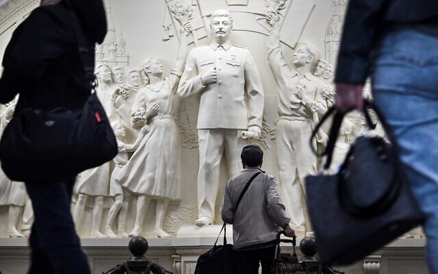 Des usagers de métro font une pause en passant devant le bas-relief récemment dévoilé représentant le dictateur soviétique Joseph Staline dans un passage de la station de métro Taganskaïa à Moscou, le 15 mai 2025. Le 15 mai 2025, les autorités moscovites ont dévoilé un bas-relief représentant Joseph Staline dans le métro de la capitale russe, alors que le Kremlin s'efforce depuis des années de réhabiliter le dictateur, en promouvant une version ultra-patriotique de l'histoire qui passe sous silence la répression de l'ère soviétique. Le métro de Moscou a dévoilé la réplique du bas-relief du dictateur soviétique à l'intérieur de la station centrale Taganskaïa, qui avait été détruite dans les années 1960 lors de la campagne de déstalinisation. (Crédit : Alexander NEMENOV / AFP)