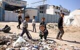 Des enfants jouant autour de déchets devant le siège fermé du très controversé Office de secours et de travaux des Nations unies pour les réfugiés de Palestine dans le Proche-Orient (UNRWA), à Gaza, le 20 mai 2025. (Crédit : Bashar Taleb/AFP)