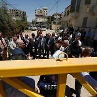 Des membres d'une délégation diplomatique de l'Union européenne derrière un portail à l'entrée est du camp de Jénine, lors d'une visite dans la ville de Cisjordanie, le 21 mai 2025. (Crédit : Mohammad Mansour/AFP)
