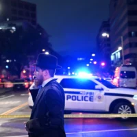 Un homme juif, debout derrière un ruban de la police américaine, parle sur son téléphone portable à l'extérieur du Capital Jewish Museum après une fusillade qui a fait deux morts, à Washington, DC, le 21 mai 2025. (Crédit : Alex WROBLEWSKI / AFP)