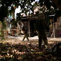 Des soldats israéliens patrouillent près d'une maison incendiée au kibboutz Kissufim, dans le sud d'Israël, le 21 octobre 2023. (Crédit : AP Photo/Francisco Seco)