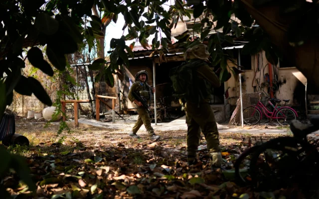 Des soldats israéliens patrouillent près d'une maison incendiée au kibboutz Kissufim, dans le sud d'Israël, le 21 octobre 2023. (Crédit : AP Photo/Francisco Seco)
