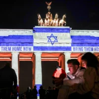 La porte de Brandebourg est illuminée par le drapeau d'Israël à Berlin, Allemagne, le 7 octobre 2024, pour marquer le premier anniversaire du massacre perpétré par le Hamas le 7 octobre en Israël. (Crédit : Kay Nietfeld/dpa via AP)