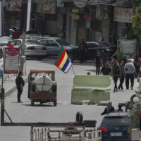Des hommes armés druzes se tiennent à côté du drapeau religieux de leur secte à un poste de contrôle à l'une des entrées de la banlieue de Jaramana, après des affrontements dans la zone entre les membres de la secte minoritaire druze et les combattants pro-gouvernementaux, dans la banlieue sud de Jaramana, à Damas, en Syrie, le 30 avril 2025. (Crédit : Omar Sanadiki/AP)