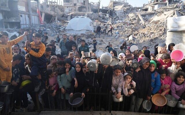 Des Palestiniens attendant la distribution de vivres dans un centre d'aide humanitaire à Beit Lahiya, dans le nord de la bande de Gaza, le 16 mars 2025. (Crédit : Abdel Kareem Hana/AP)