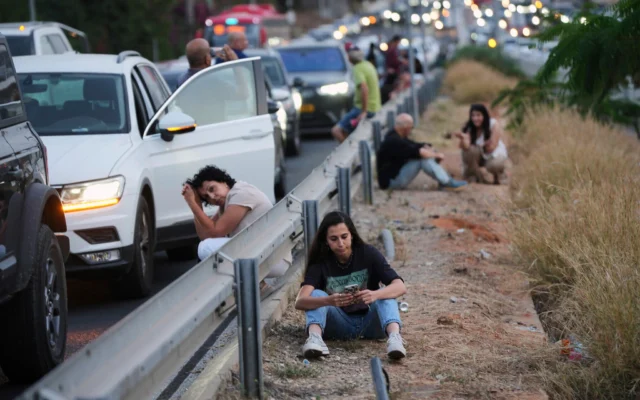 Des Israéliens se mettent à l'abri sur le bord d'une autoroute alors que les sirènes sont activées à la suite d'un missile lancé depuis le Yémen, à Tel Aviv, Israël, le 13 mai 2025. (Crédit : AP Photo/Ohad Zwigenberg) Des Israéliens se mettent à l'abri sur le bord d'une autoroute alors que les sirènes sont activées à la suite d'un missile lancé depuis le Yémen, à Tel Aviv, Israël, le 13 mai 2025. (Crédit : AP Photo/Ohad Zwigenberg)