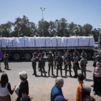 Un camion chargé d'aide humanitaire pour la bande de Gaza se dirigeant vers le poste-frontière de Kerem Shalom, tandis que des policiers empêchent des militants de bloquer la route dans le sud d'Israël, le 21 mai 2025. (Crédit : Ohad Zwigenberg/AP)