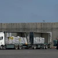 Un ouvrier déchargeant la cargaison d’un camion transportant de l’aide humanitaire pour la bande de Gaza dans la zone de déchargement du poste-frontière de Kerem Shalom entre Israël et Gaza, le 22 mai 2025. (Crédit : Leo Correa/AP)