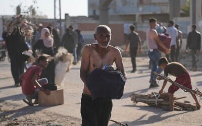 Des Palestiniens transportant des cartons contenant de la nourriture et des colis d'aide humanitaire livrés par la Gaza Humanitarian Foundation, une organisation soutenue par les États-Unis et approuvée par Israël, à Rafah, dans le sud de la bande de Gaza, le 27 mai 2025. (Crédit  : Abdel Kareem Hana/AP)