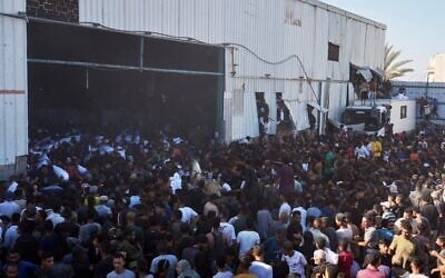 Des Palestiniens prenant d'assaut un entrepôt du Programme alimentaire mondial des Nations unies et emportant des sacs de farine à Zawaida, Deir Al-Balah, dans le centre de la bande de Gaza, le 28 mai 2025. (Crédit : Abdel Kareem Hana/AP)