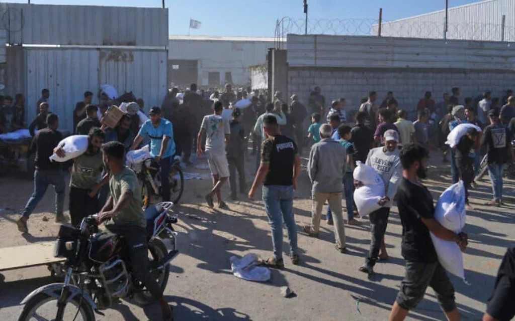 Illustration : Des Palestiniens transportant des sacs de farine après avoir pris d'assaut un entrepôt du Programme alimentaire mondial des Nations unies, à Zawaida, Deir Al-Balah, dans le centre de la bande de Gaza, le 28 mai 2025. (Crédit : Abdel Kareem Hana/AP)
