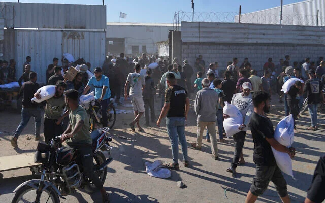 Illustration : Des Palestiniens transportant des sacs de farine après avoir pris d'assaut un entrepôt du Programme alimentaire mondial des Nations unies, à Zawaida, Deir Al-Balah, dans le centre de la bande de Gaza, le 28 mai 2025. (Crédit : Abdel Kareem Hana/AP) Illustration : Des Palestiniens transportant des sacs de farine après avoir pris d'assaut un entrepôt du Programme alimentaire mondial des Nations unies, à Zawaida, Deir Al-Balah, dans le centre de la bande de Gaza, le 28 mai 2025. (Crédit : Abdel Kareem Hana/AP)
