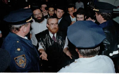 Des Juifs orthodoxes parlent avec la police du besoin de davantage de présence policière de façon à prévenir de nouvelles violences lors des émeutes anti-juives dans le quartier de Crown Heights, à Brooklyn, dans l'Etat de New York, le 21 août 1991. (Crédit : AP Photo/Andrew Savulich)