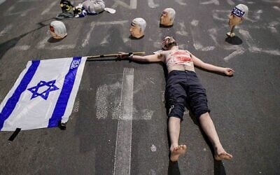 Des masques à l'effigie du Premier ministre Benjamin Netanyahu entourent un manifestant portant de faux bandages sanguinolents lors d'une manifestation anti-gouvernementale à Tel Aviv, le 26 avril 2025. (Crédit : Tomer Neuberg/Flash90)