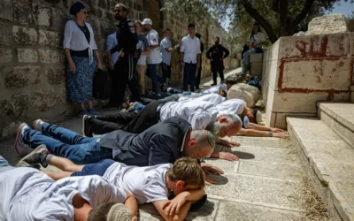 Le député Otzma Yehudit Yitzhak Kroizer (en blazer bleu) parmi plusieurs Juifs prosternés sur le mont du Temple sous le regard des policiers, lors de la Journée de Jérusalem, le 26 mai 2025. (Crédit : Yonatan Sindel/Flash90)