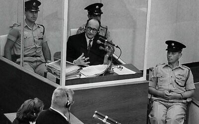 Le criminel de guerre nazi Adolf Eichmann se tient dans une cabine de protection en verre, entouré de la police israélienne, lors de son procès le 22 juin 1961 à Jérusalem. (Crédit : Bureau du Premier ministre)