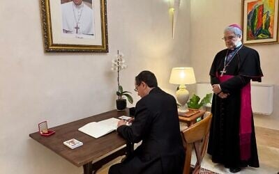 Le président israélien Isaac Herzog, signe le livre de condoléances à l’ambassade du Vatican à Jaffa, le 2 mai, 2025 (Crédit : Capture d’écran/X ; utilisée conformément à la clause 27a de la loi sur le droit d'auteur)