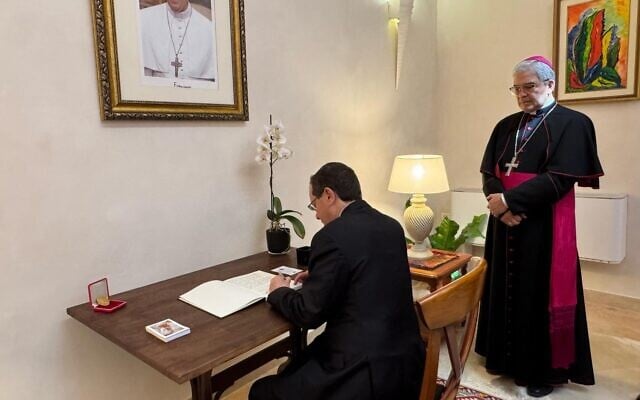 Le président israélien Isaac Herzog, signe le livre de condoléances à l’ambassade du Vatican à Jaffa, le 2 mai, 2025 (Crédit : Capture d’écran/X ; utilisée conformément à la clause 27a de la loi sur le droit d'auteur)