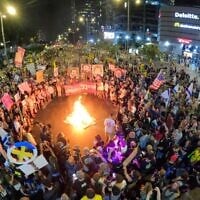 Des manifestants réclamant un accord pour la libération des otages allumant un feu de joie sur la route à la fin d'un rassemblement à la porte Begin, à Tel Aviv, le 17 mai 2025. (Crédit : Gilad Furst/Mouvement de protestation pour la démocratie)