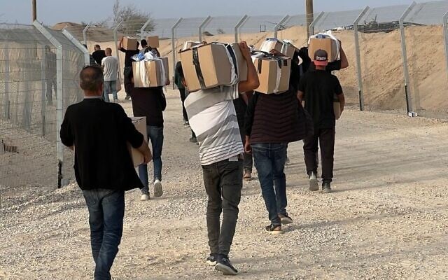 Des Palestiniens récupèrent des cartons d'aide humanitaire sur un site de distribution géré par la Fondation humanitaire de Gaza, le 26 mai 2025. (Crédit : GHF) Des Palestiniens récupèrent des cartons d'aide humanitaire sur un site de distribution géré par la Fondation humanitaire de Gaza, le 26 mai 2025. (Crédit : GHF)