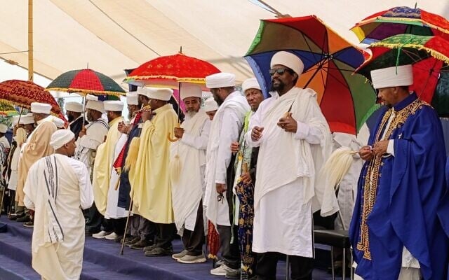 Des prêtres éthiopiens, ou « Kohanim », se tenant debout avec leurs parapluies lors de la cérémonie commémorative nationale en hommage aux Juifs éthiopiens, le 26 mai 2025. (Crédit : Zev Stub/Times of Israel)