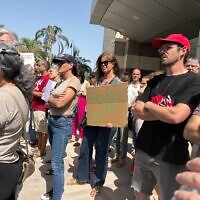 Des enseignants et des militants rassemblés pour protester contre le renvoi potentiel de l'enseignant Storm Tzemach, qui, selon eux, est puni pour avoir réclamé des salaires équitables, devant le ministère de l'Éducation à Tel Aviv, le 11 mai 2025. (Crédit : Ariela Karmel/Times of Israel)