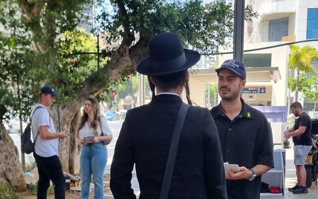 Naor Narkis discutant avec un passant, à Bnei Brak, en mai 2025. (Crédit : Alexandra Vardi)