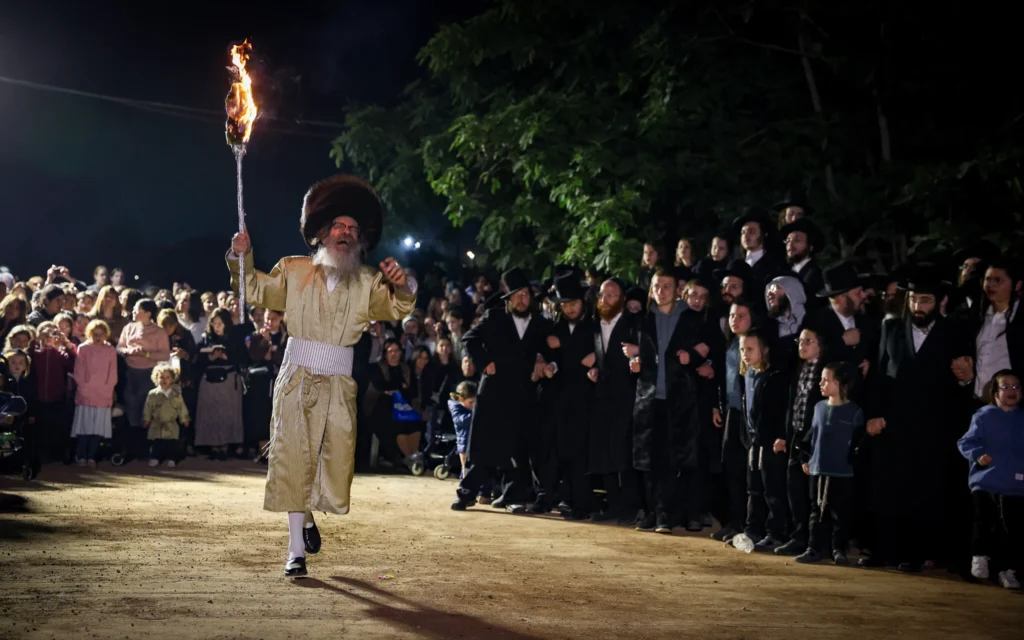 Le rabbin Nachman Biderman et ses fidèles allument un feu de joie lors des célébrations de Lag BaOmer, à Meron, le 16 mai 2025 (Crédit : David Cohen/Flash90)