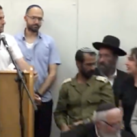 Shaked Gez (deuxième à partir de la droite) s'adresse au chef du Conseil régional de Samarie, Yossi Dagan (à gauche), lors des funérailles de sa sœur Tzeela à Jérusalem, le 15 mai 2025. (Crédit : Capture d'écran ; utilisée conformément à l'article 27a de la loi sur les droits d'auteur)